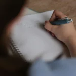 A person writing on a paper, likely working on a test