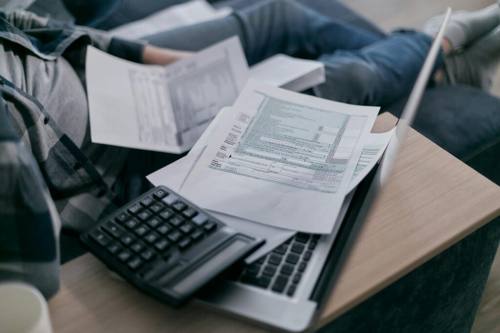 Close-up of financial documents, a calculator, and a laptop.